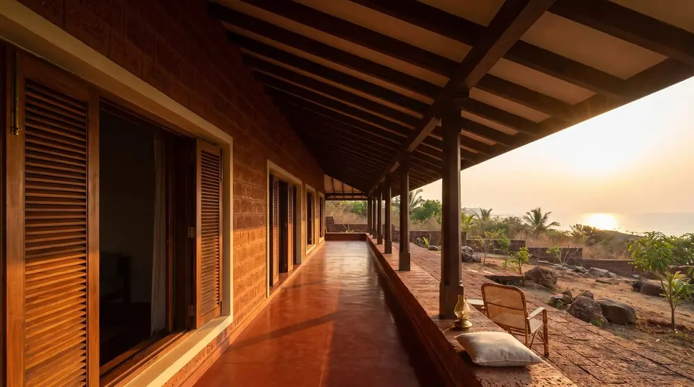 Concept image of a long laterite veranda with timber posts looking out to a sunset.