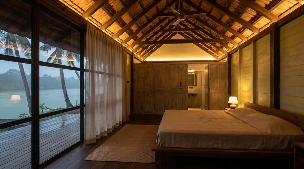 Concept image of a timber-roofed bedroom with a glass wall onto the backwater.