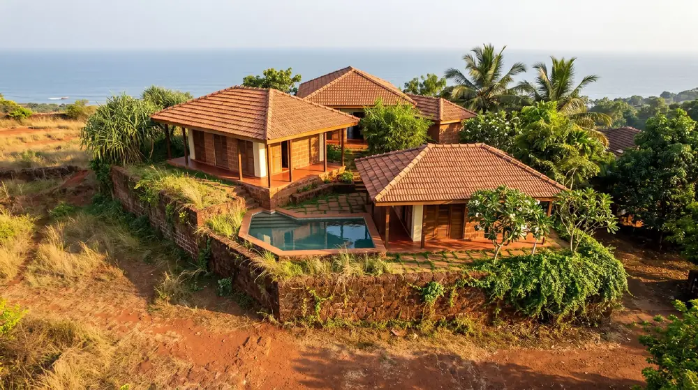 Concept image of three tiled-roof laterite houses on a coastal plateau above the Arabian Sea.